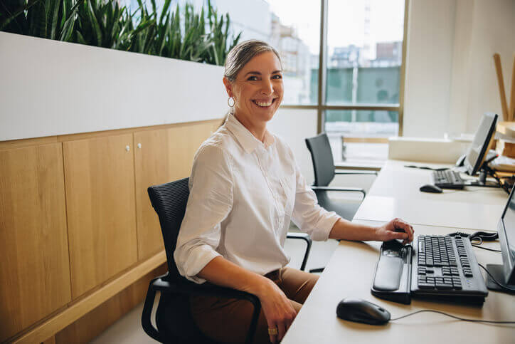 Friendly female Office Administrator in an office after completing an office administration course online in BC