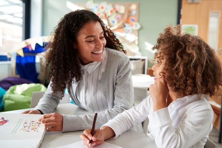 An educational assistant training program graduate working one-on-one with a student during learning activities