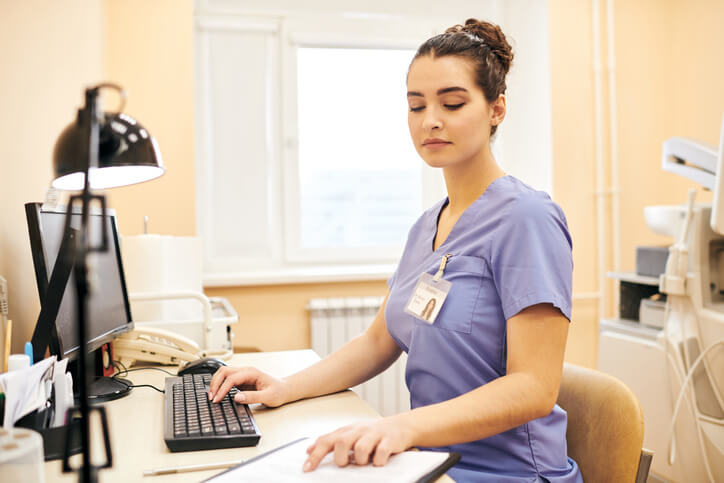 A medical assistant preparing patient records in a clinic