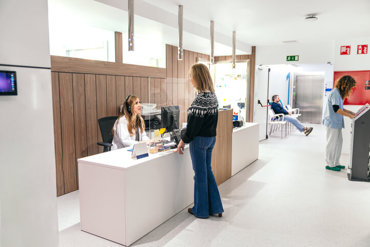 A medical office assistant program grad helping a patient at a busy clinic.